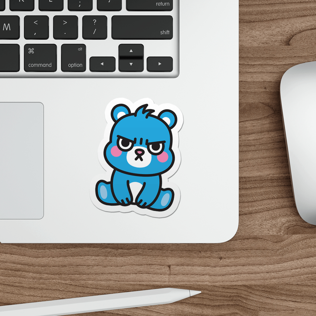 Laptop with a sticker of a grumpy teddy bear on a wooden desk.