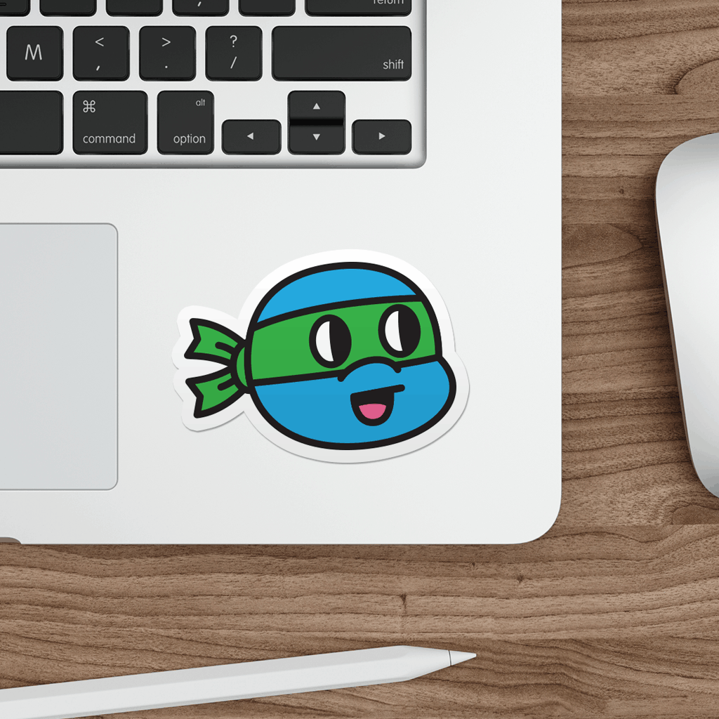 Laptop with a sticker of a cartoon ninja turtle on a wooden desk.