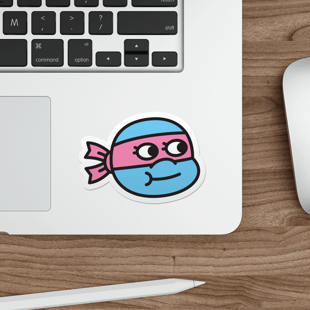Laptop with a sticker of a cartoon ninja turtle on a wooden desk.