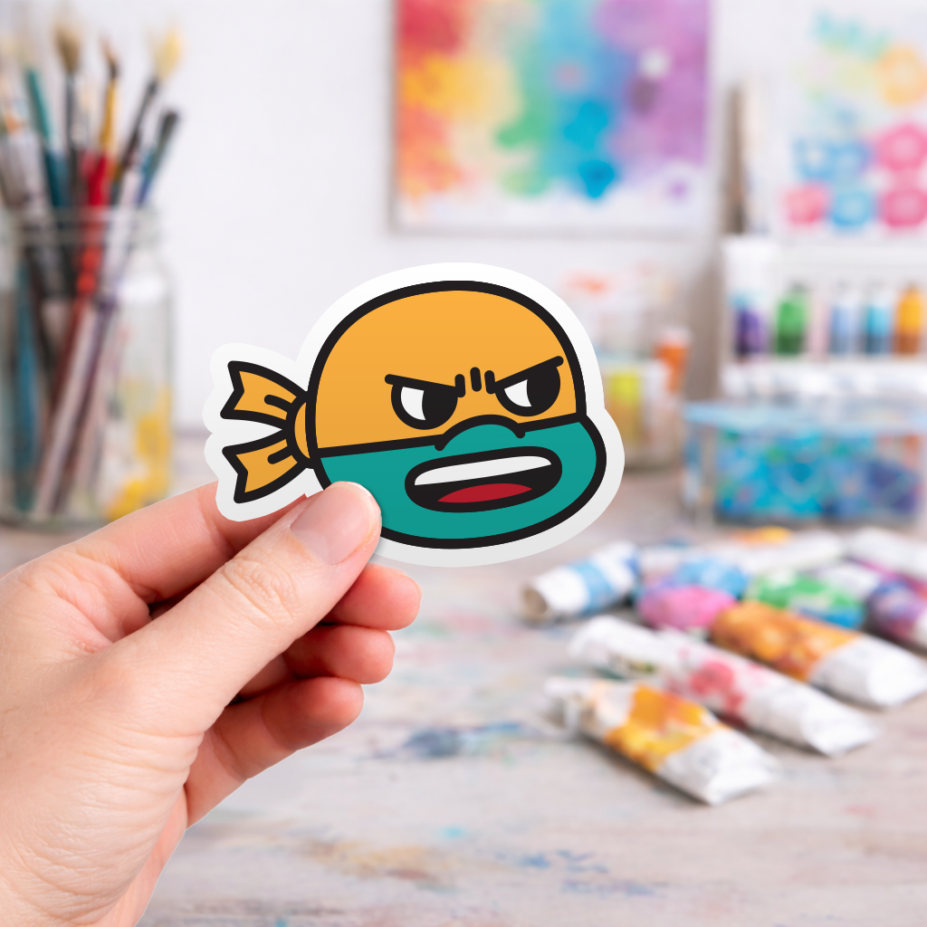 Hand holding a colorful laptop sticker of a cartoon ninja turtle character