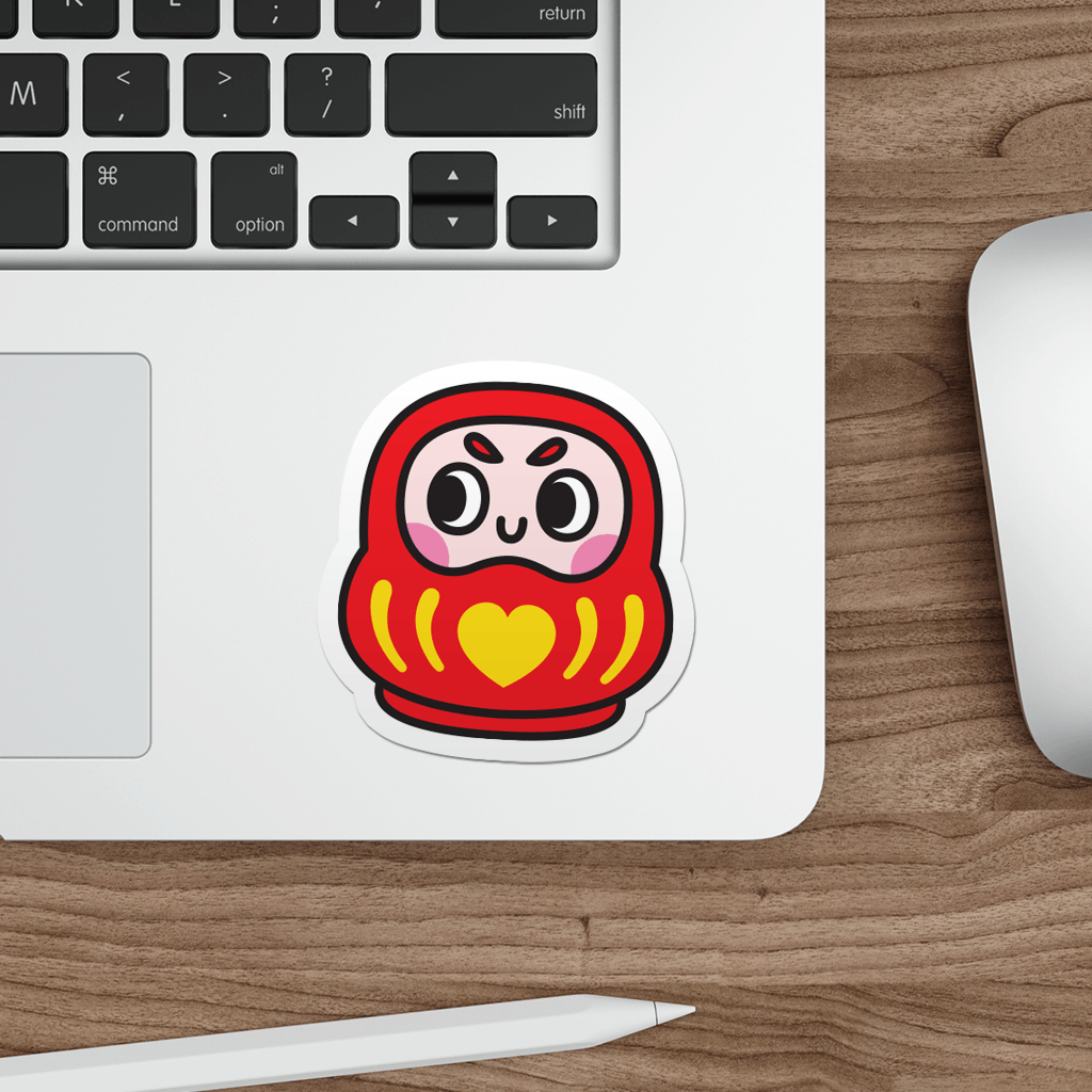 Laptop with a sticker of a daruma doll on a wooden desk.