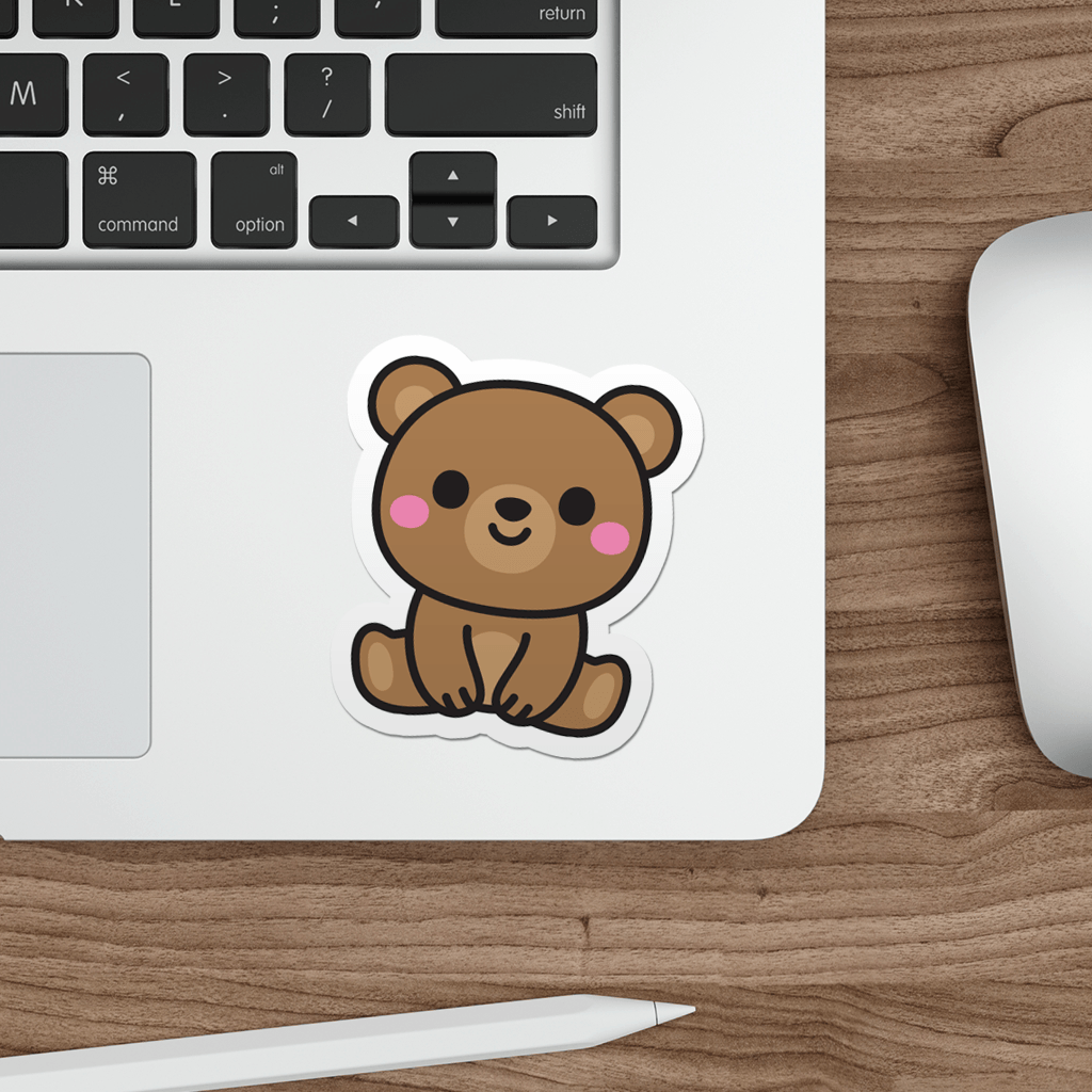 Laptop with a sticker of a cute brown teddy bear on a wooden desk.